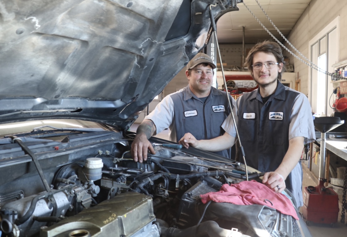 Auto technicians working on engine repair inside auto repair shop